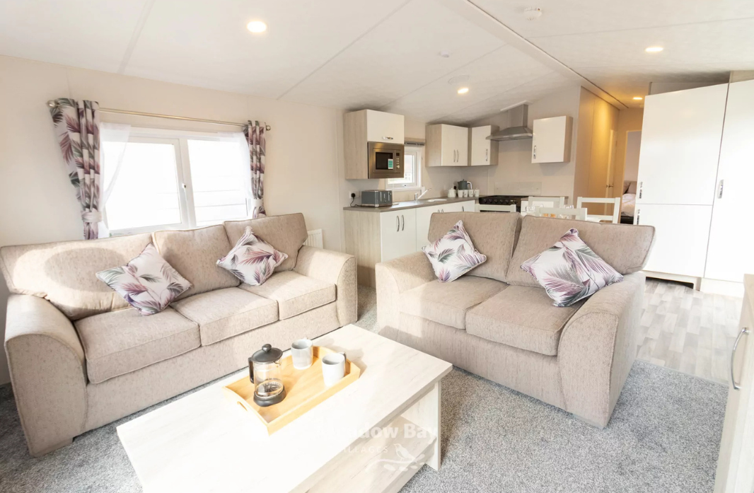 Spacious holiday home living area with comfortable sofas and open-plan kitchen at Meadow Bay Villages