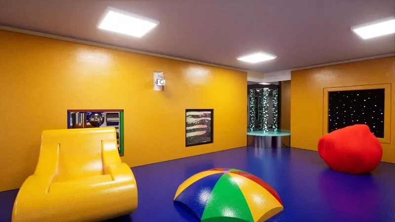 A yellow room with a large chair and objects of different shapes