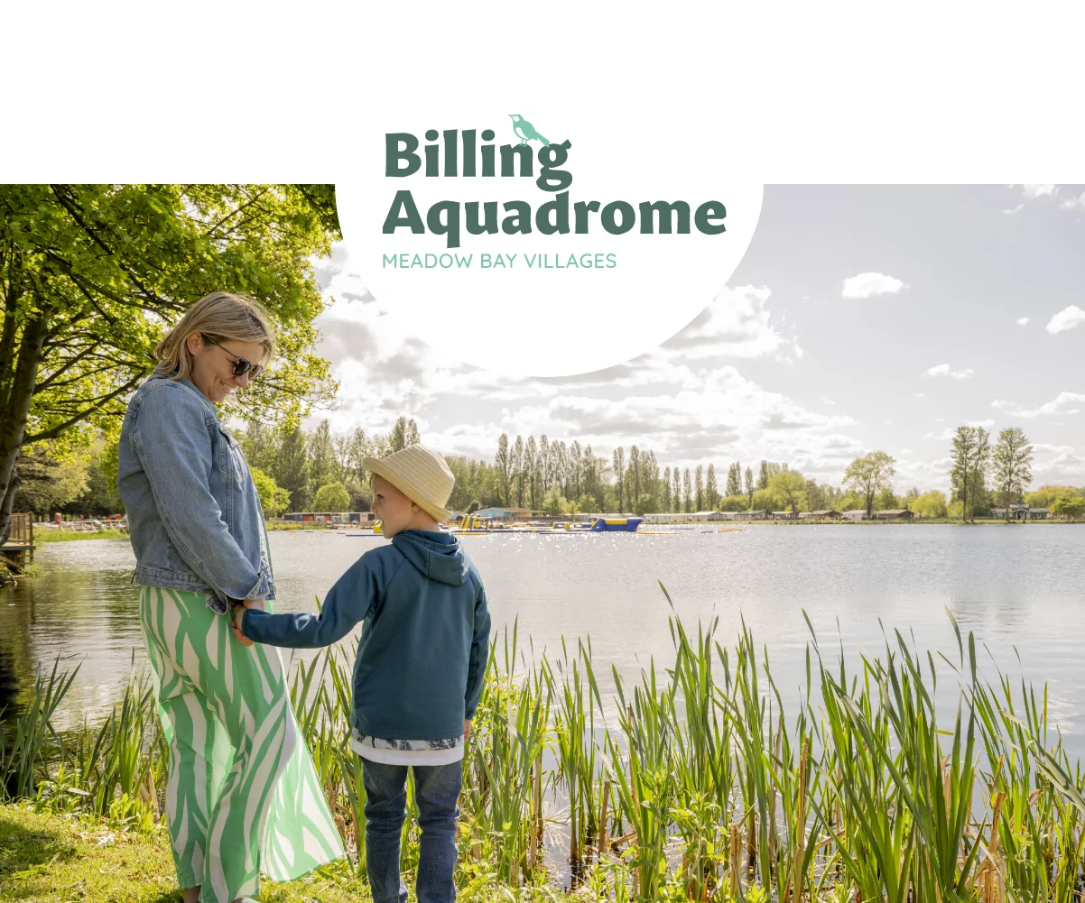 Woman and child enjoying a peaceful moment by the lakeside at Billing Aquadrome holiday park under the trees on a sunny day.