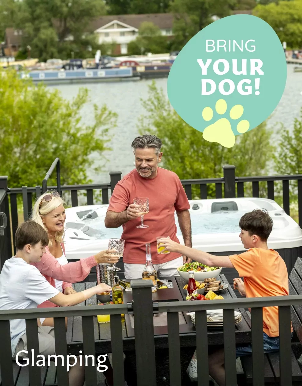 A family enjoying an outdoor meal on the decking of a glamping lodge with a hot tub, in a dog-friendly setting at Meadow Bay Villages.