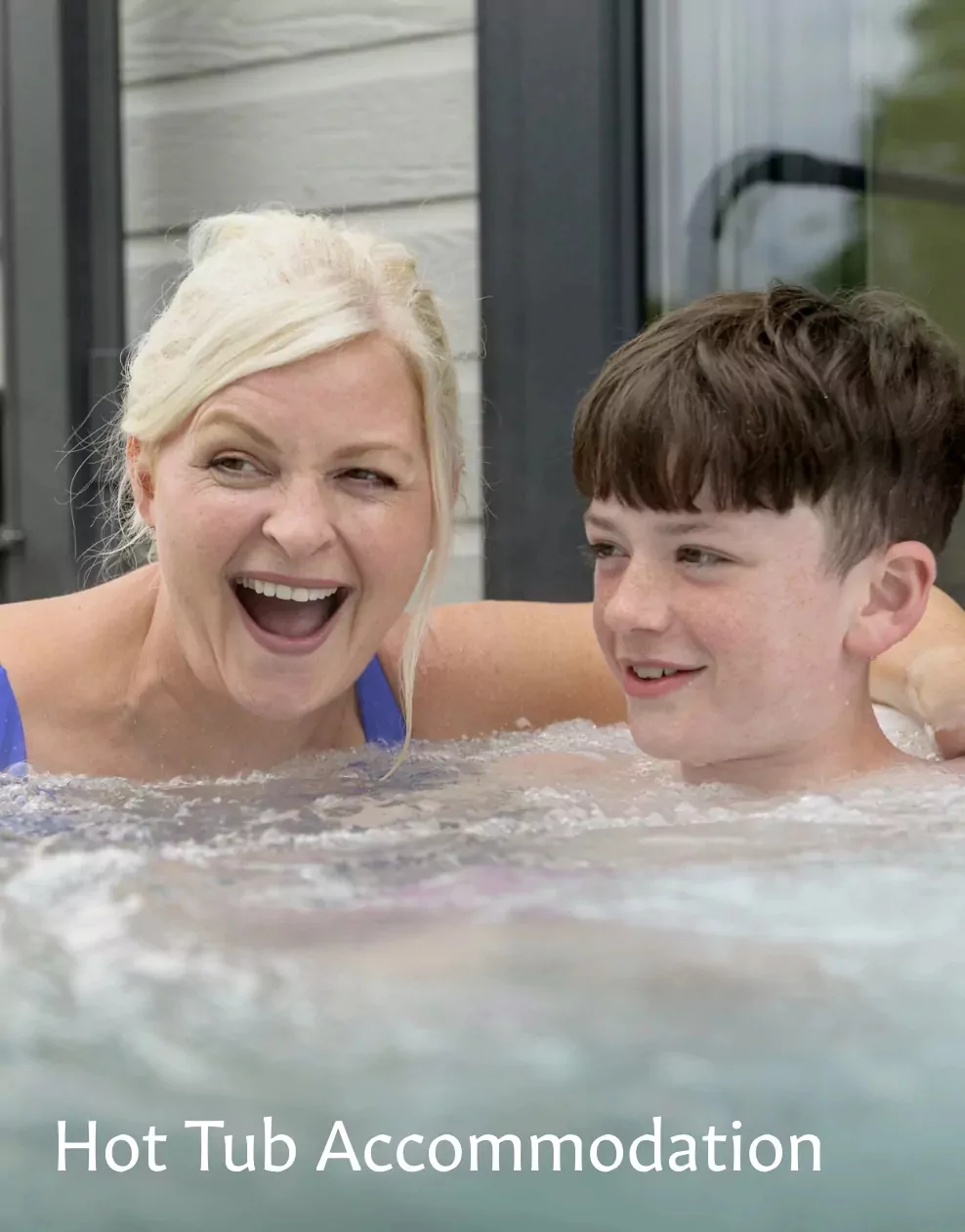 A mother and son smiling and relaxing together in a hot tub at Meadow Bay Villages.