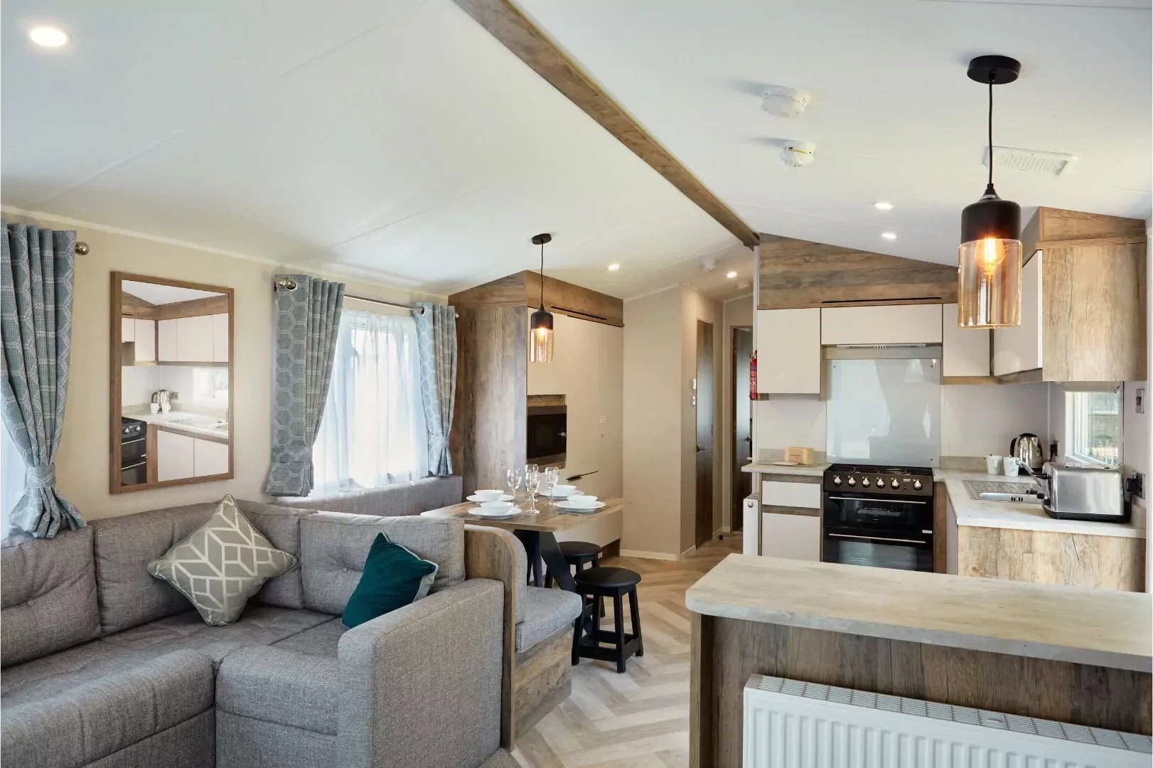 Spacious open-plan kitchen and lounge area inside a Meadow Bay Villages holiday lodge with stylish wood finishes and dining space.