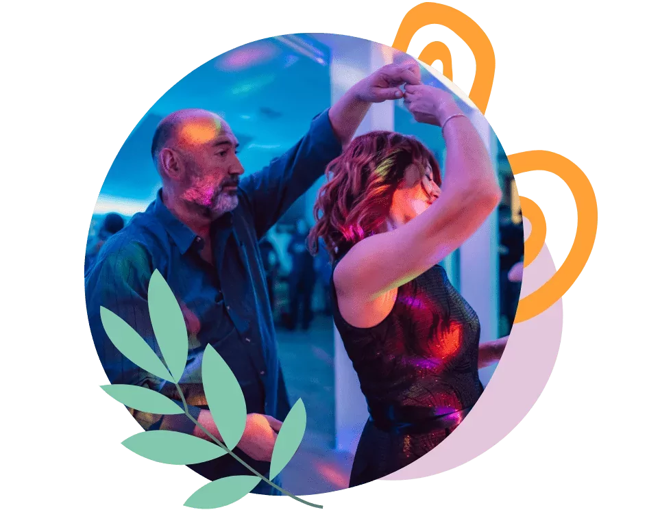 Couple dancing together in a lively dance class at Meadow Bay Villages, with colourful lighting and social atmosphere.
