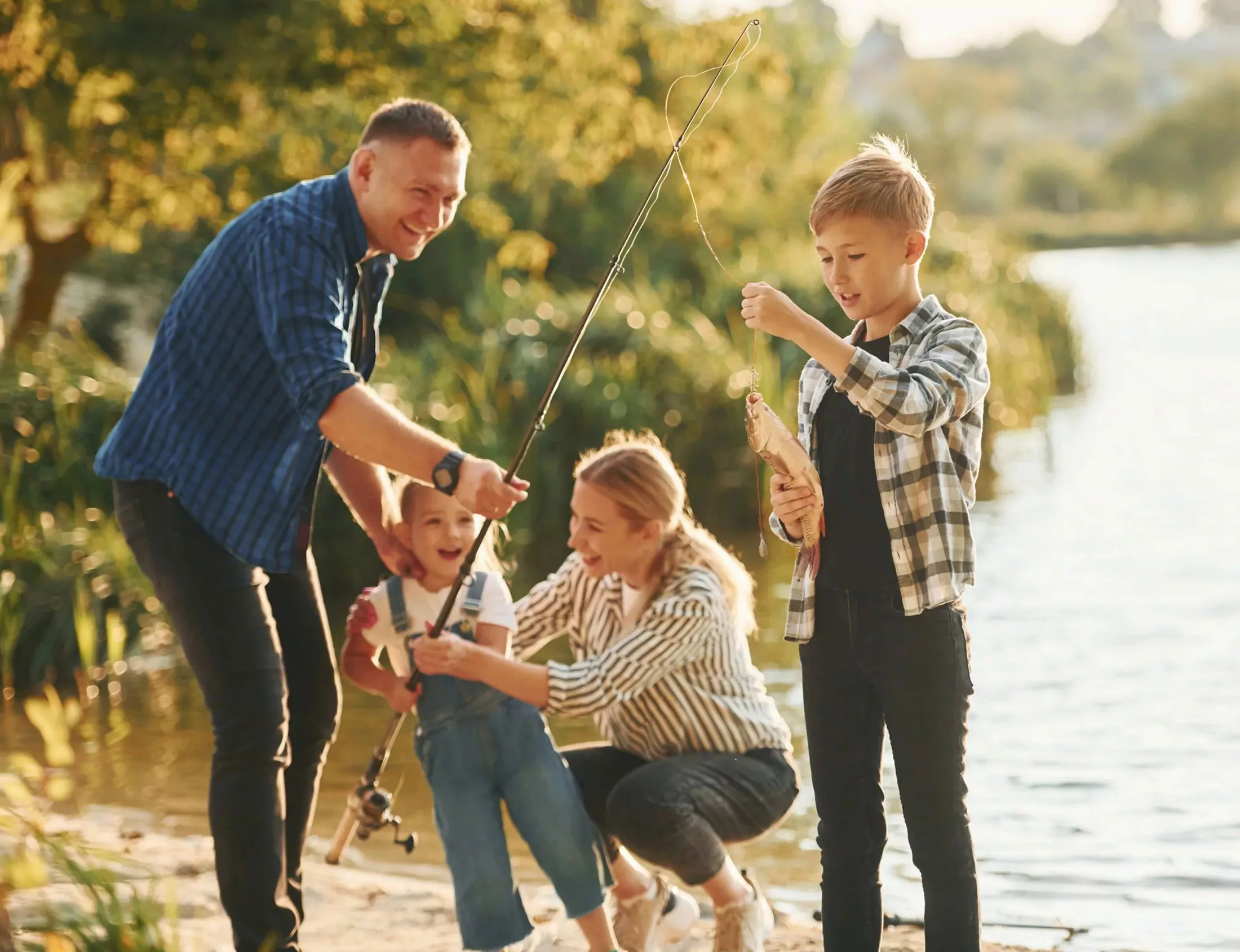 Family fishing by the lake at Meadow Bay Villages with a child proudly holding a fresh catch, enjoying quality time together.