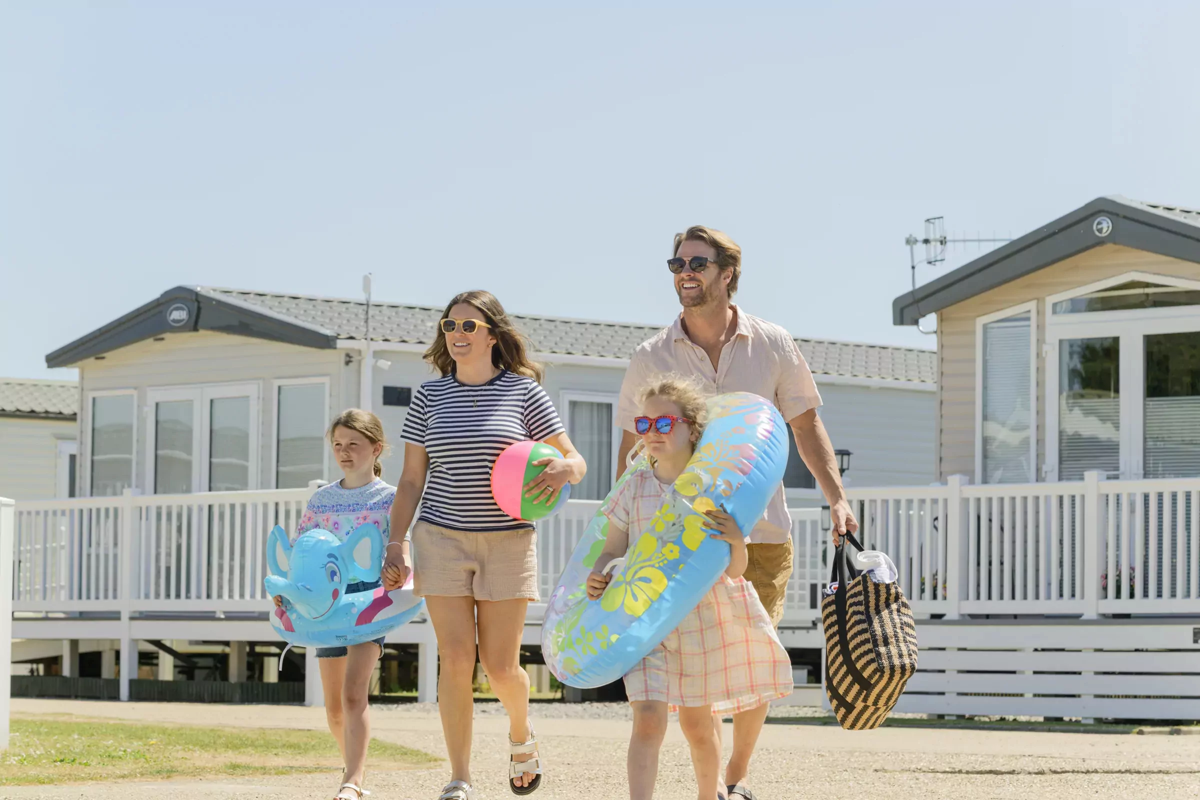 Family carrying pool floats and beach toys at Meadow Bay Villages holiday park