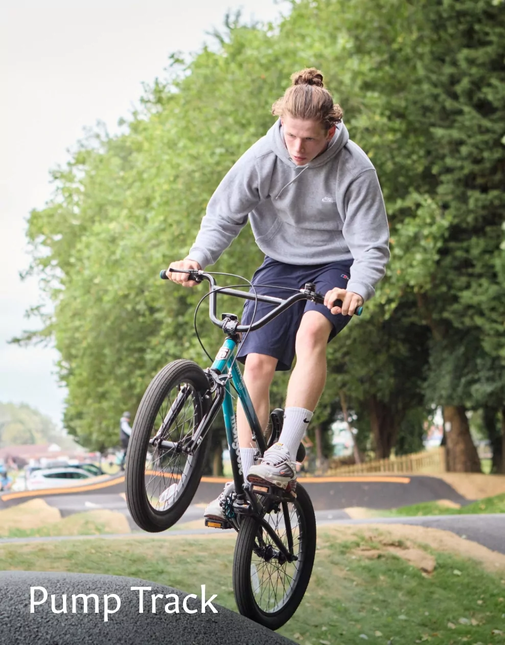 A young man riding a BMX bike over a ramp on the pump track at Meadow Bay Villages.
