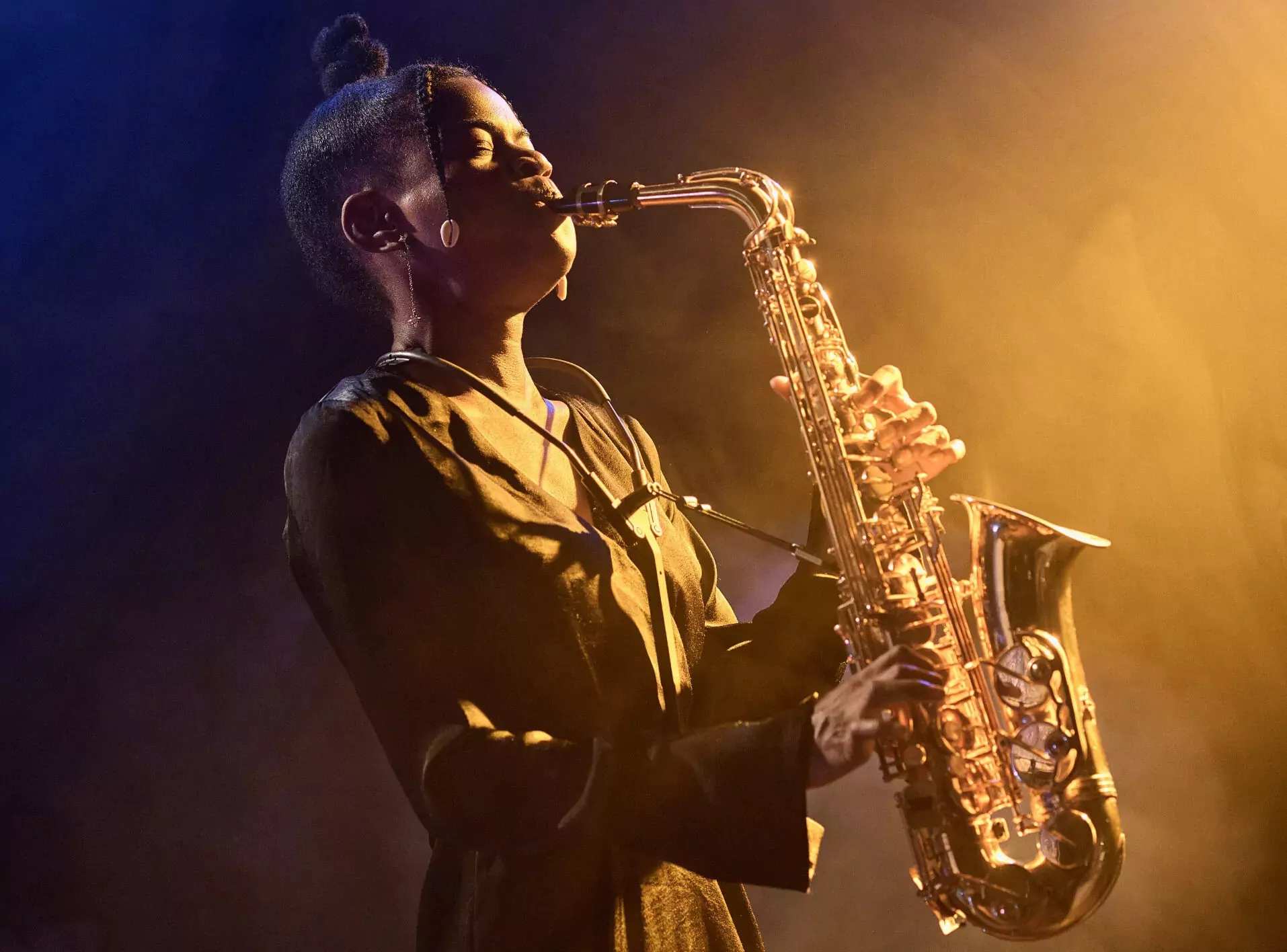 Female jazz saxophonist performing on stage in moody lighting during a Meadow Bay Villages evening event.