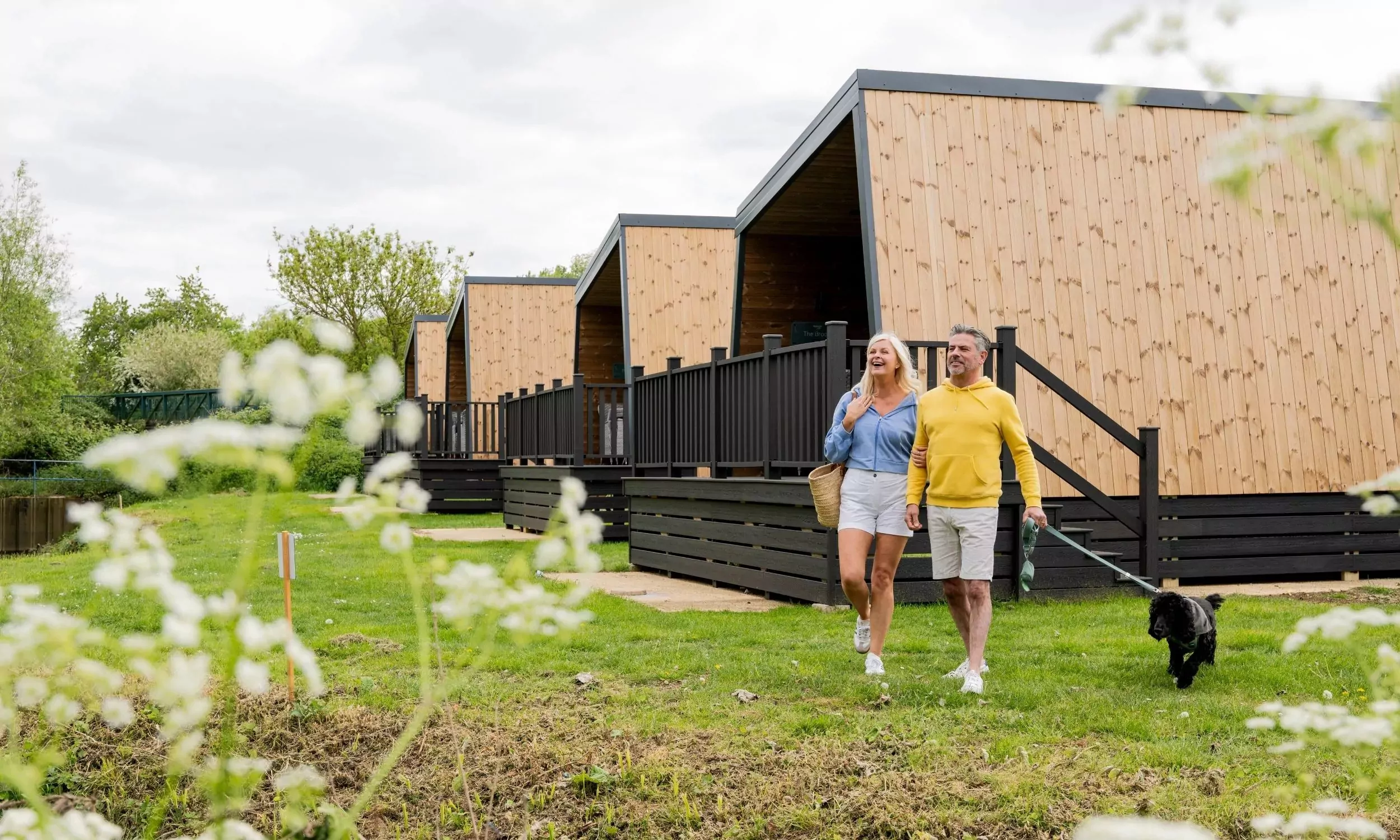 Couple walking their dog along the luxury glamping pods at Billing Aquadrome Holiday Park