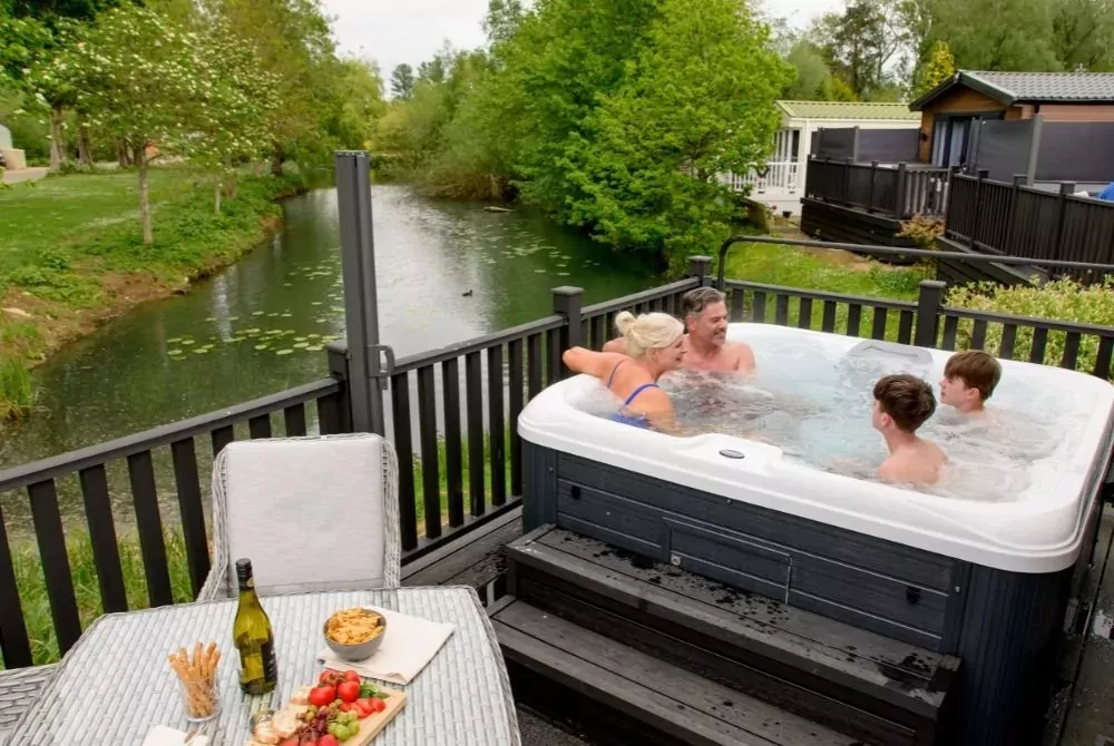 Family relax in a hot tub on the decking of a holiday home
